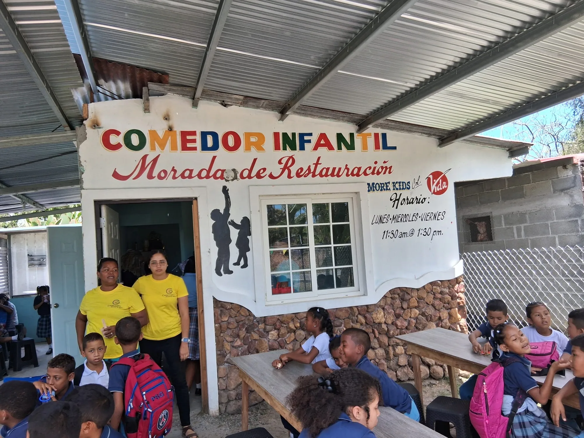 Children and volunteers gather outside the community meal center