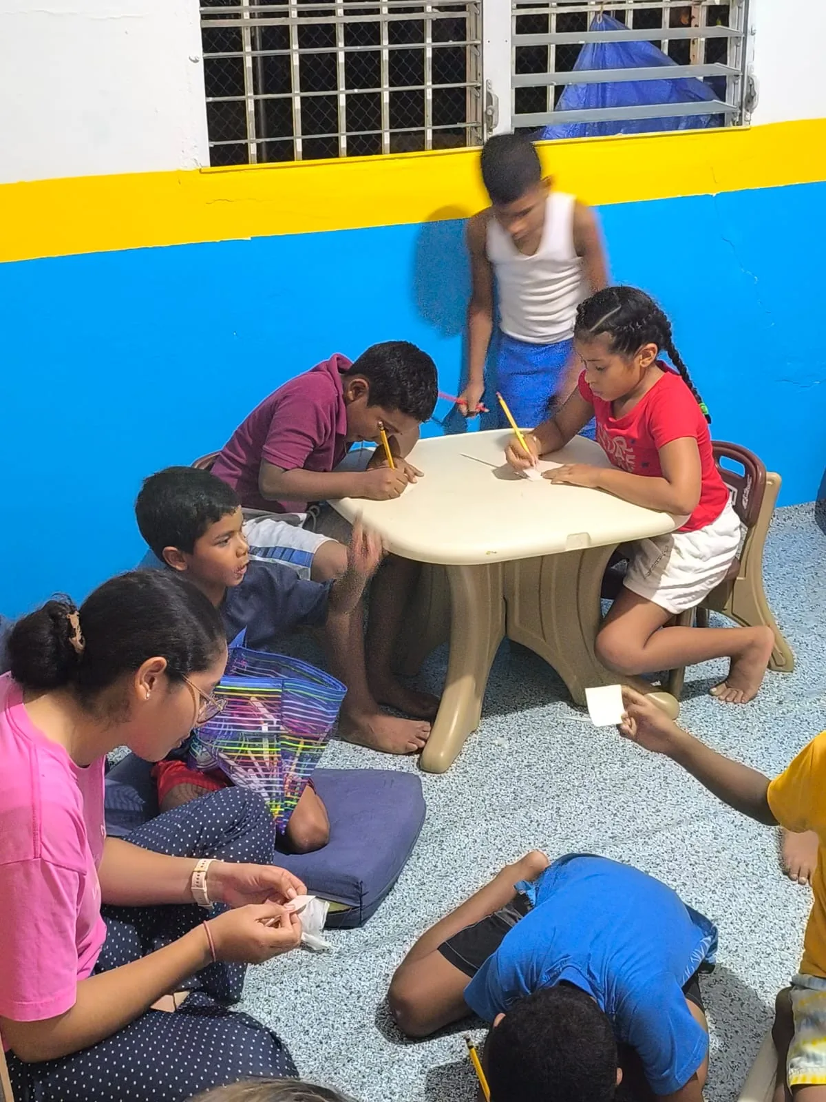 Children draw and complete activities together at a table in the center