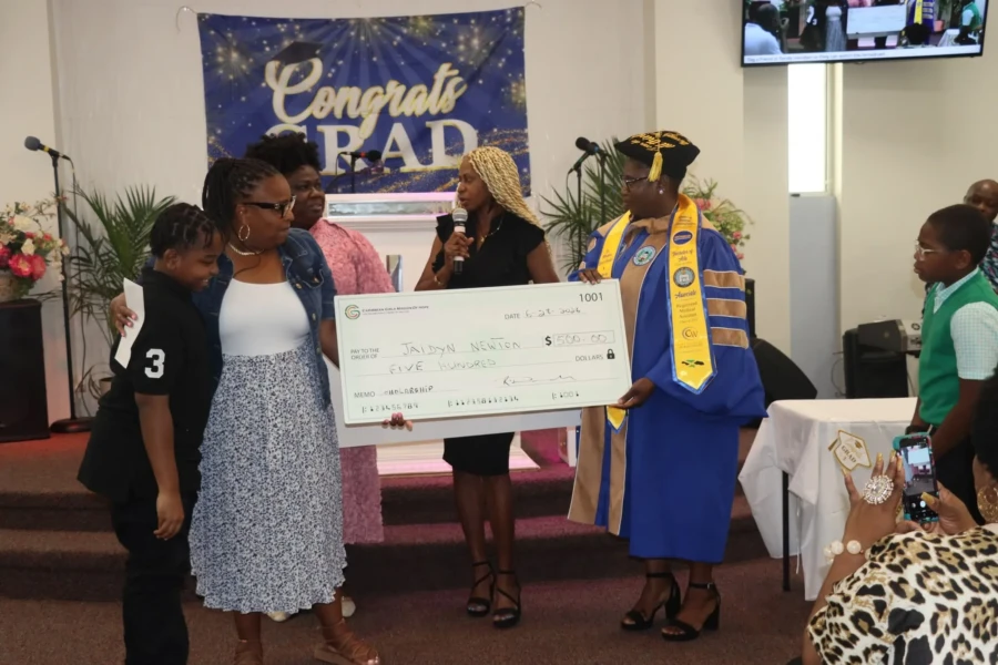 A graduate and CGMOH representatives display a ceremonial scholarship check
