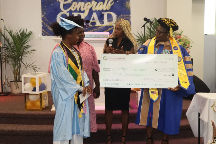 A scholarship recipient in graduation attire poses with CGMOH representatives