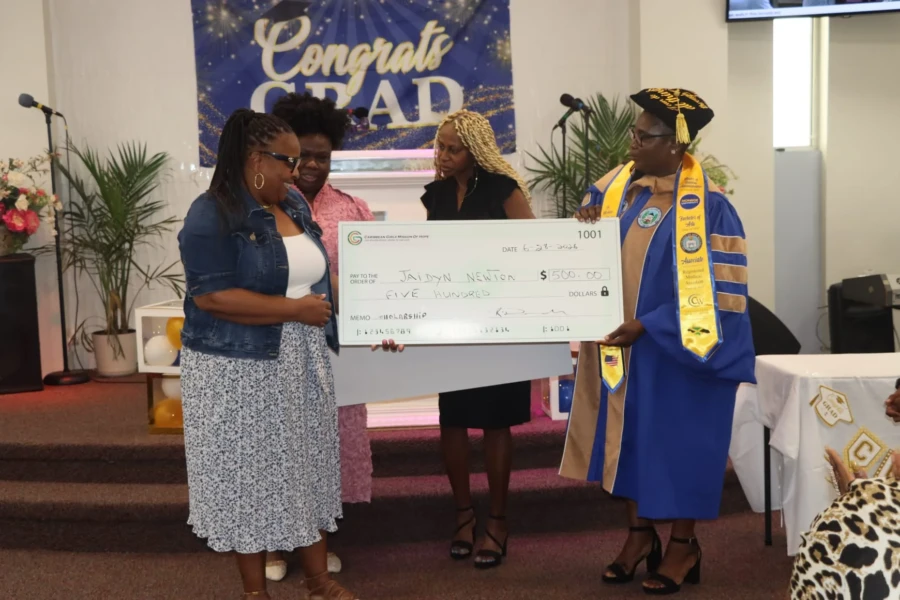 A graduate and community leaders display a CGMOH scholarship award