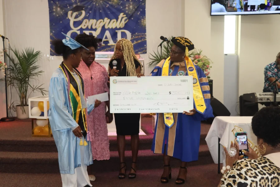 A graduate poses with CGMOH representatives and a ceremonial scholarship check