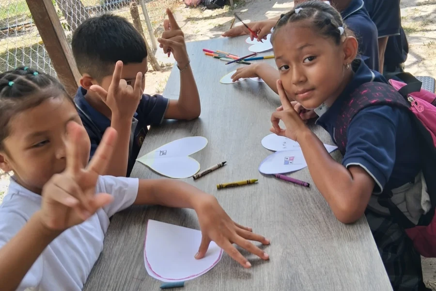 Children smile and display their paper crafts during the activity day