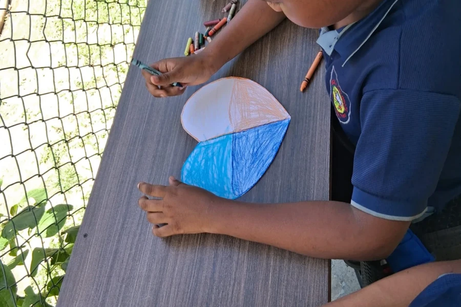 A student colors a paper fish during the children's arts-and-crafts activity