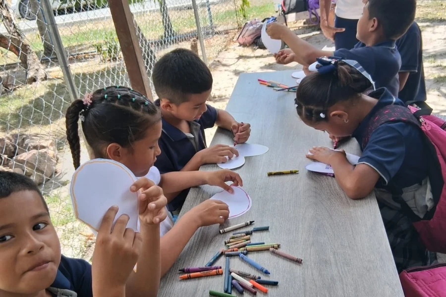 Children create paper crafts together at an outdoor table