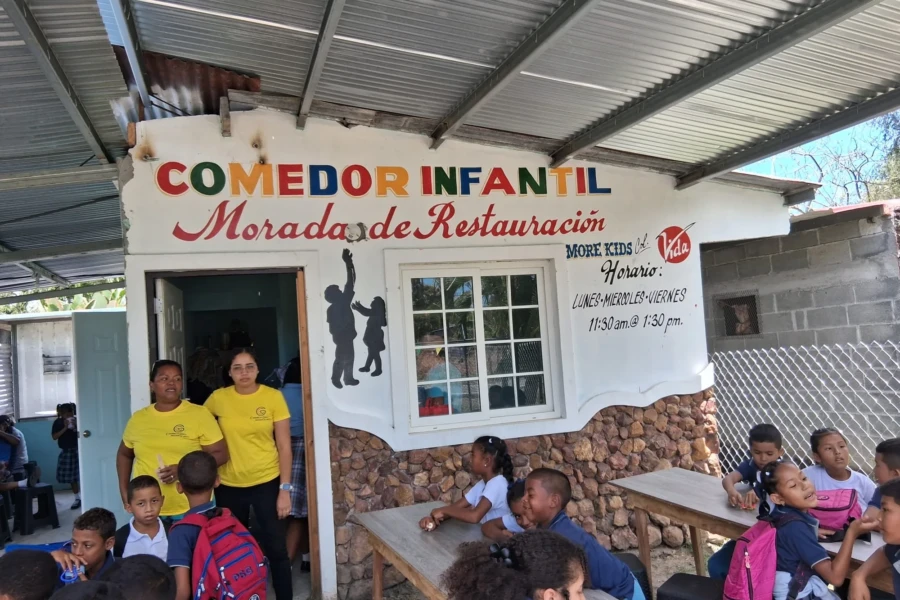Children and volunteers gather outside the community meal center