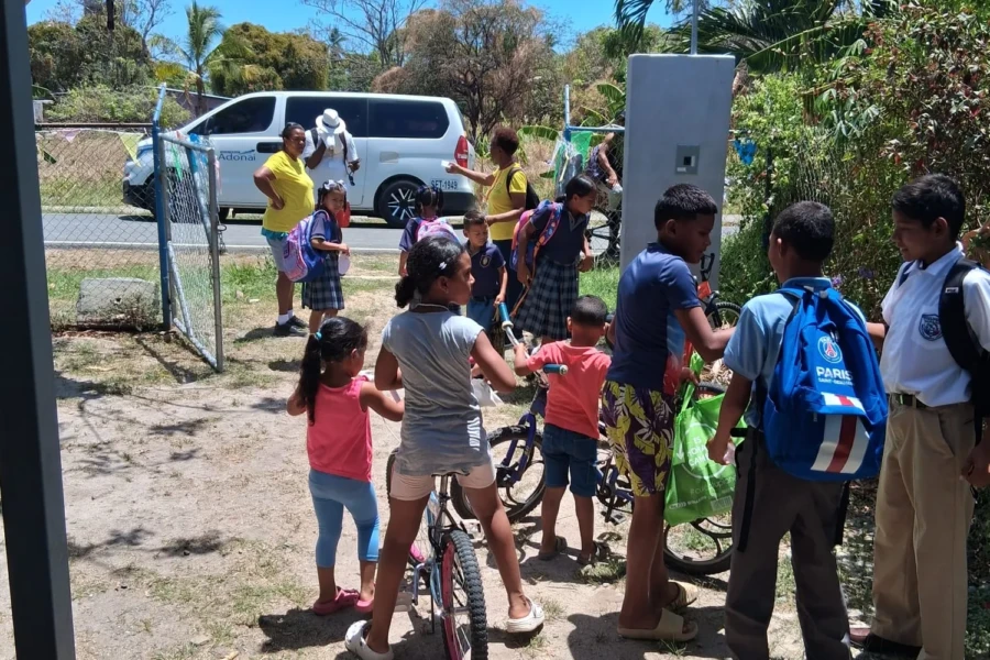 Children gather outdoors with school bags and bicycles after the activity