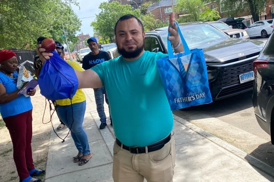 A smiling father holds a blue care bag received at the giveaway
