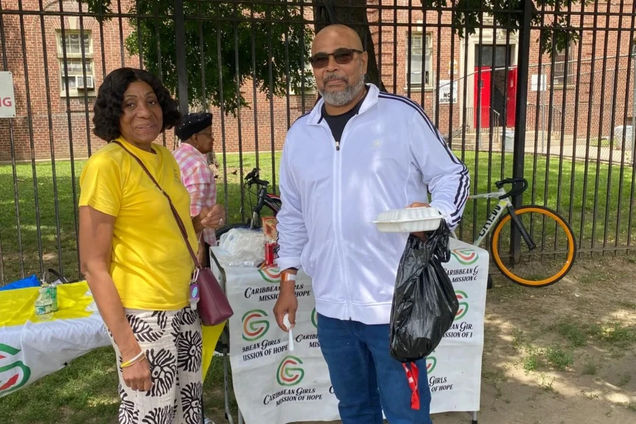 A volunteer poses with a father holding food and a care package