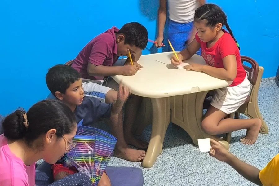 Children draw and complete activities together at a table in the center