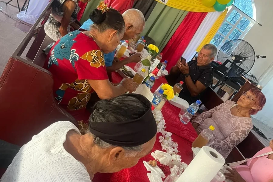 Older adults and volunteers gather around a decorated table during the Guyana outreach