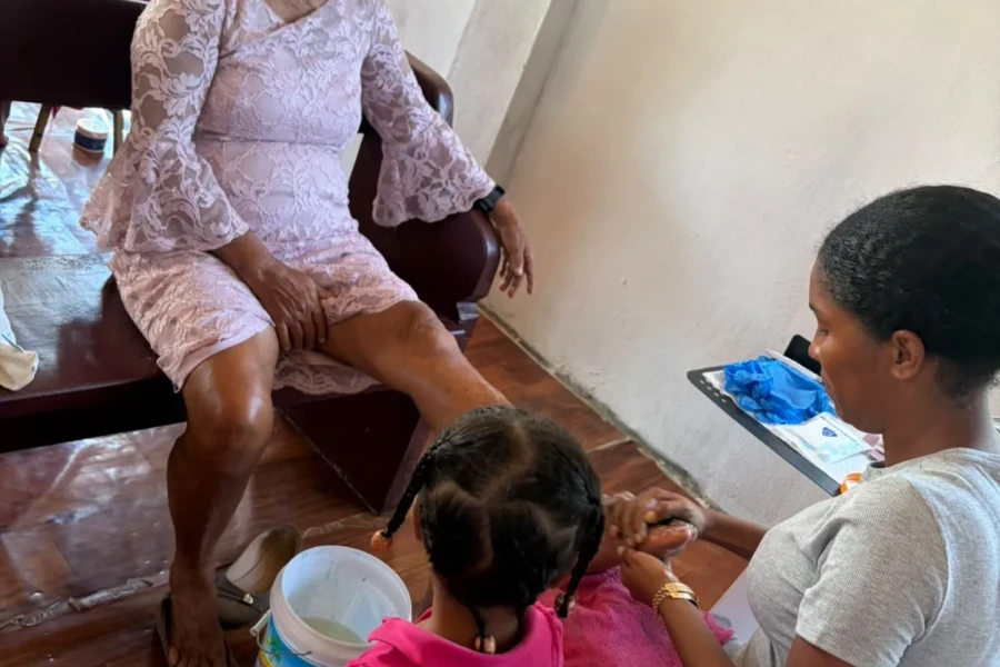 A family and volunteer spend time with an older woman during the outreach