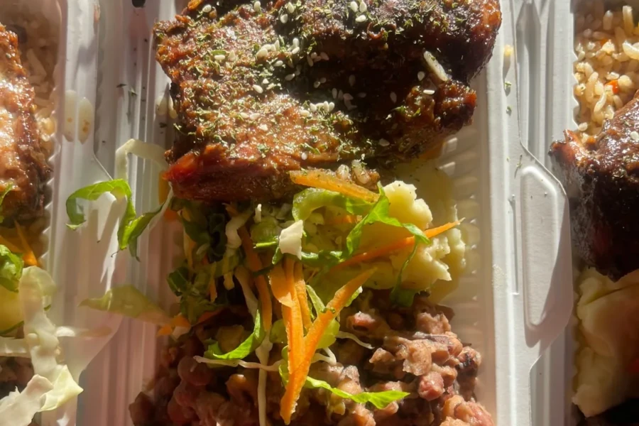 A prepared meal with rice, vegetables and a glazed entree ready for distribution