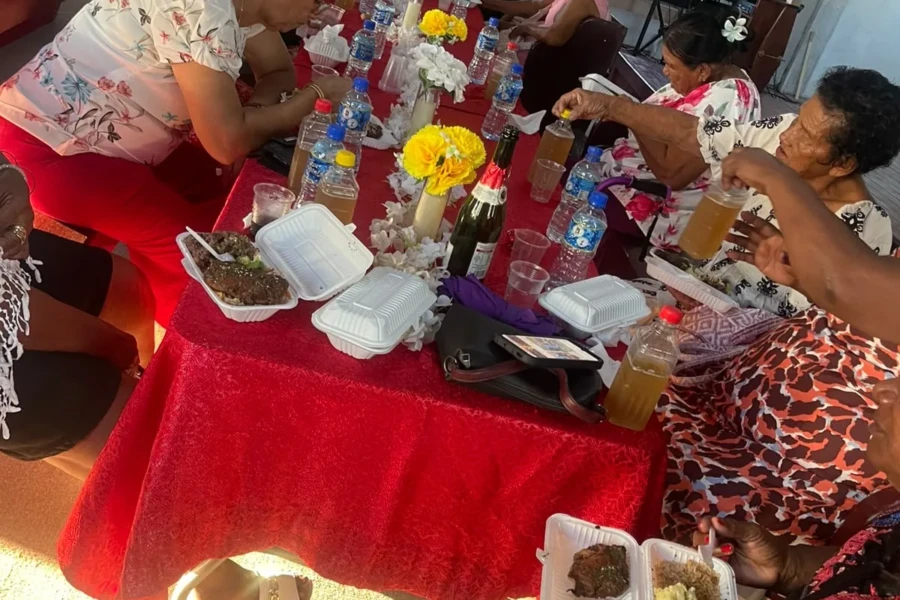 Volunteers serve meals to older adults seated around the outreach table