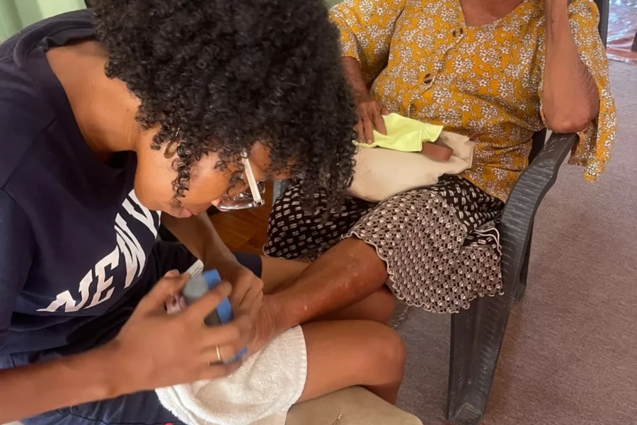 A volunteer carefully provides foot care to an older adult