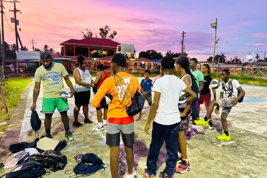 Young people gather around donated sports gear on a Kawkani basketball court