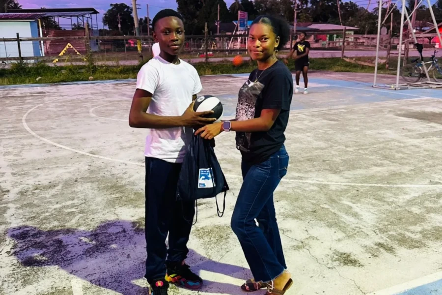 Two young people display a donated drawstring bag on the basketball court