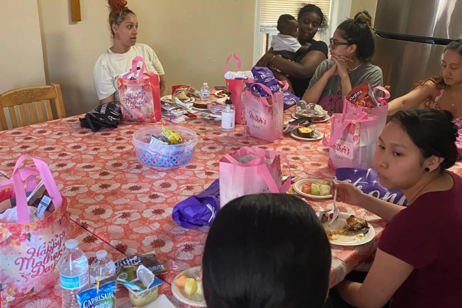 Mothers gather around a decorated table with gifts during the CGMOH celebration
