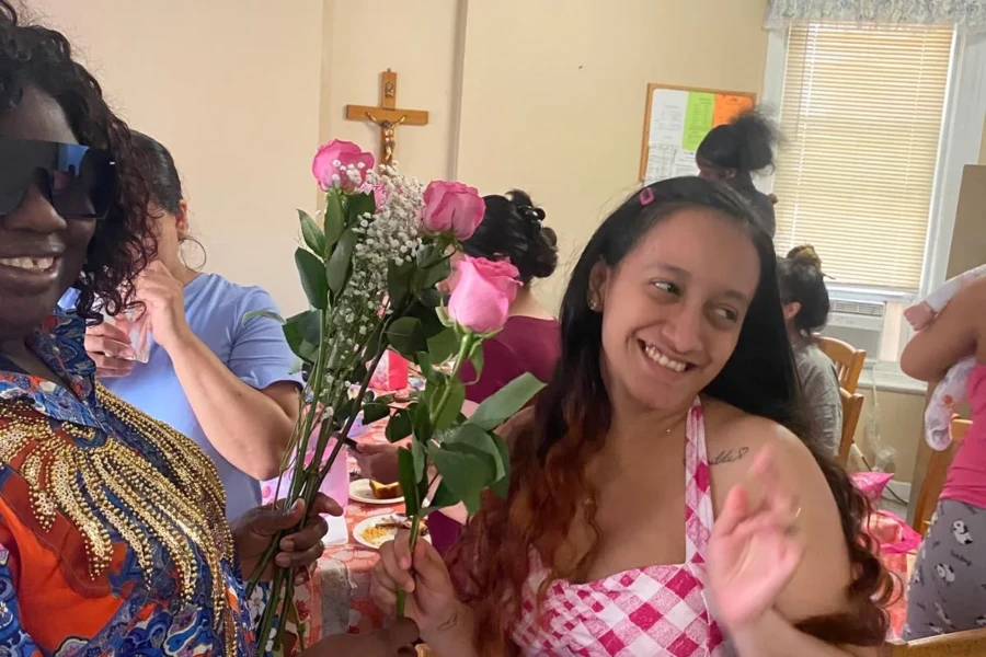 A smiling guest holds roses presented at the Mother's Day gathering