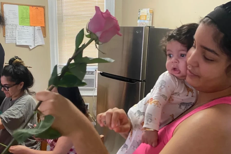 A mother holding her baby receives a rose during the celebration