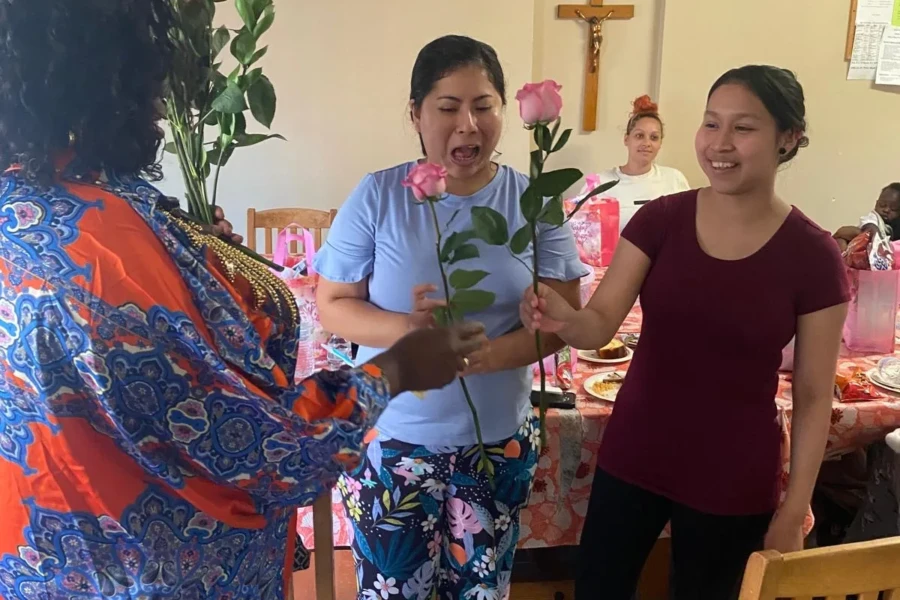 Two guests smile as they receive roses from a CGMOH volunteer