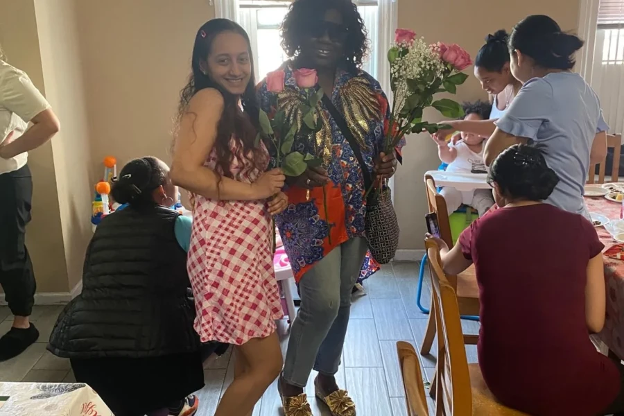 A CGMOH volunteer presents a rose and gift to a Mother's Day guest