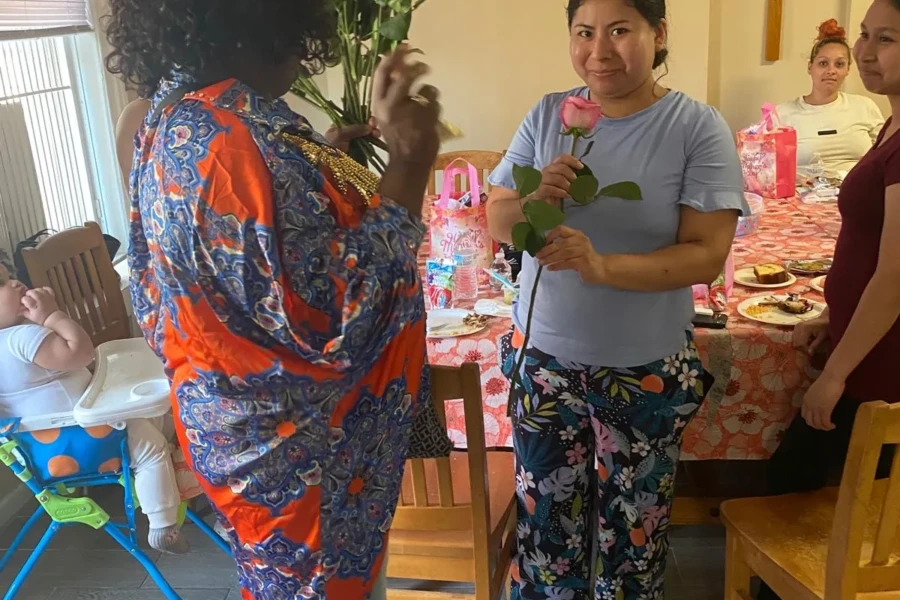 A woman receives a rose from a CGMOH volunteer beside the celebration table